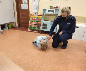 Policjantka pokazuje na przykładzie dziecka jak chronić się przed atakującym psem.