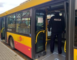 Umundurowany policjant kontroluje autobus MPK