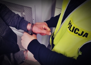 Policjant zakładający kajdanki zatrzymanemu mężczyźnie