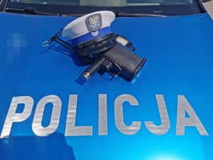 Czapka policyjna i fotoradar leżące na masce radiowozu