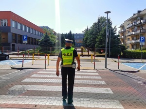 Umundurowany policjant przechodzi przez przejście dla pieszych