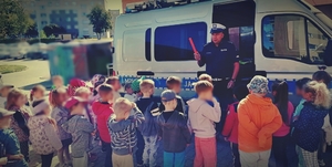 Policjant przy radiowozie rozmawiający z dziećmi
