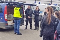 Wizyta w Komendzie Miejskiej Policji w Łomży.  Na zdjęciu technik kryminalistyki pokazuje młodzieży przyrządy, które służą do wymiarowania na miejscu wypadku drogowego.