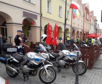 na zdjęciu widać dwa motocykle policyjne dwóch stojących obok policjantów, z których jeden tłumaczy coś młodej kobiecie