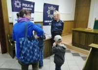 policjantka przy stoliku rozmawia z kobietą, której dzieci oglądają ulotki leżące na stoliku w tle rolapy Komendy Miejskiej Policji w Łomży