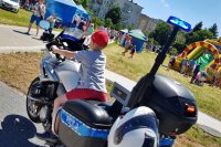 Pokaz sprzętu policyjnego. Dziecko pozuje do zdjęcia na policyjnym motocyklu.