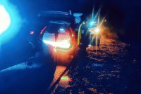 Pora nocna. Na zdjęciu widać  samochody policyjne z włączonymi światłami błyskowymi podczas kontroli zatrzymanego pojazdu.