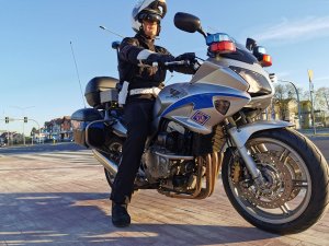 Policjant siedzący na motocyklu, w tle ulica miasta.