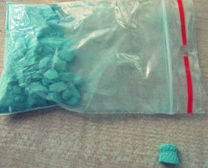 zielone tabletki w torebce zamykanej strunowo, jedna tabletka leży poza torebką