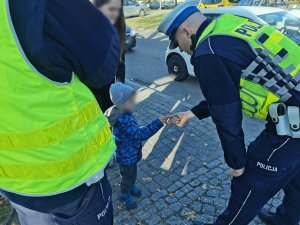 Umundurowany policjant daje odblask dziecku