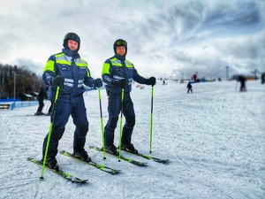 Dwóch umundurowanych policjantów z patrolu narciarskiego stoi na stoku.