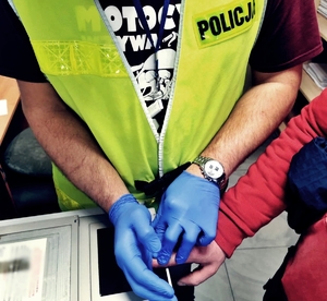 policjant zdejmuje odciski palców zatrzymanemu