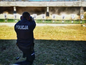 Policjant strzela w kierunku tarczy na strzelnicy