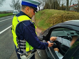 Policjant podaje czytnik do karty kierowcy, który opłaca mandat kartą bankomatową