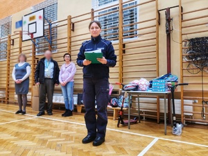 Policjantka odczytuje na sali gimnastycznej wyniku turnieju