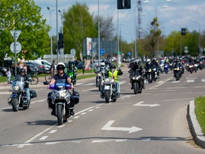 ulicą miasta jadą motocykliści. Na czele policjant na motocyklu policyjnym.