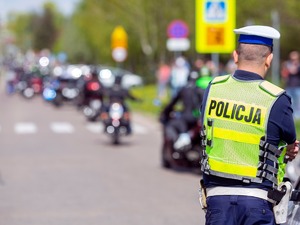 Stojący policjant, a przed nim sznur jadących motocyklistów
