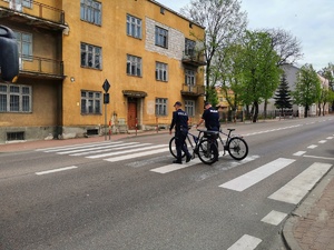 Dwóch policjantów prowadzi rower na przejściu dla pieszych