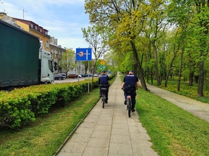 Dwóch policjantów na rowerach jedzie parkiem