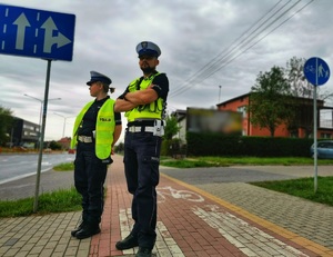 Umundurowani policjanci stoją przy przejściu dla pieszych.