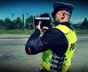 Policjant ruchu drogowego mierzy prędkość miernikiem ręcznym