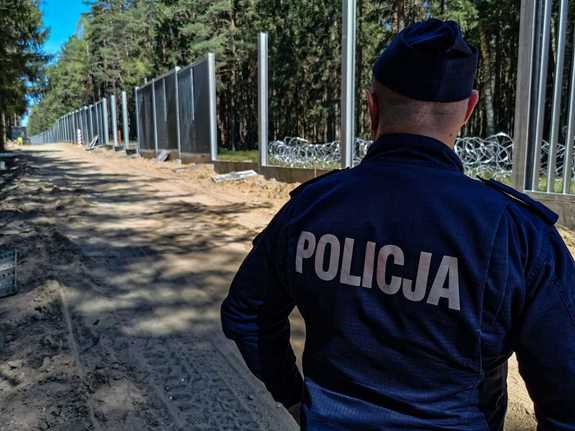 Policjant patrzący w stronę płotu na granicy polsko białoruskiej