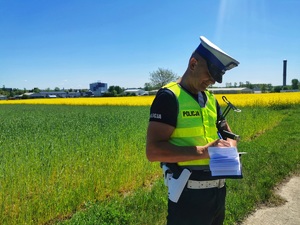 Umundurowany policjant pisze w notatniku służbowym.