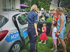 Policyjny radiowóz prezentowany przez policjantkę podczas spotkania z dziećmi