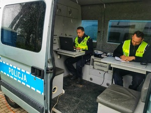 Dwóch policjantów w radiowozie sporządzają dokumentację służbową.