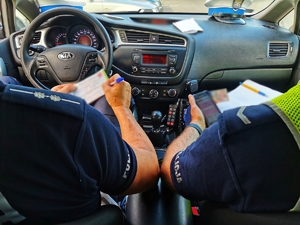 Dwóch policjantów siedzących w radiowozie