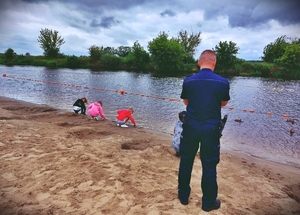 Policjant patrzący na dzieci bawiące się nad wodą