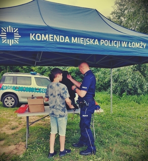 Policjant rozmawiający z dziećmi przy namiocie profilaktycznym