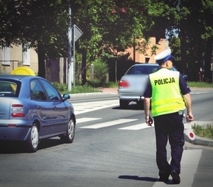 Policjant idący wzdłuż drogi, z lizakiem do zatrzymywania