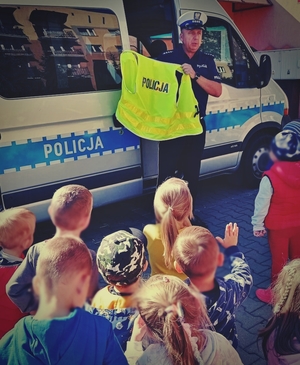 Policjant przy radiowozie rozmawia z dziećmi