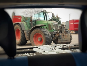 zdjęcie ze środka samochodu , rozbita tylna szyba, a w tle ciągnik rolniczy
