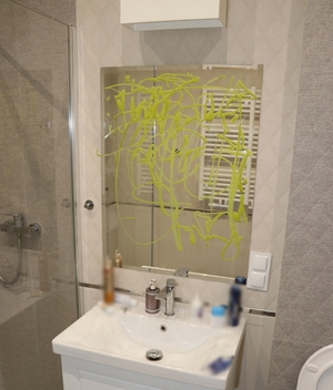 Porysowane na zielono lustro w łazience hotelowej.