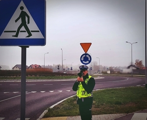 Policjant mierzący prędkość ręcznym miernikiem prędkości