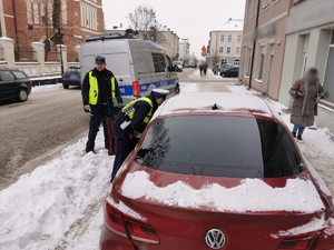 Policjanci kontrolują samochód osobowy, który stoi zaparkowany na chodniku