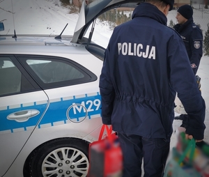 Policjanci wyjmują prezenty z radiowozu