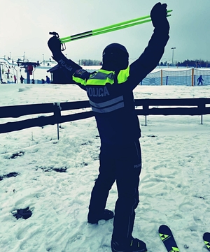 policjant w stroju narciarskim na stoku robi rozgrzewkę