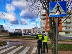 Dwóch policjantów stoi przy przejściu dla pieszych.