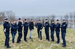 Policjantki stojące na trawie obok siebie. W tle łąki i rozlewiska.