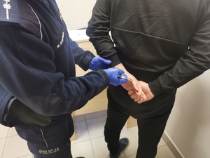 policjant zapina kajdanki zatrzymanemu