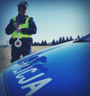 Policjant przy radiowozie z miernikiem prędkości