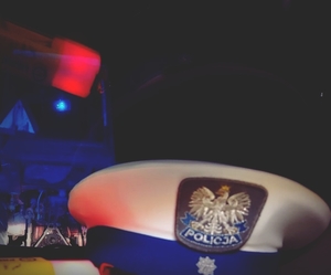 czapka policjanta ruchu drogowego i w tle ciągnik rolniczy