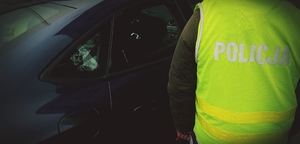 policjant stoi przy samochodzie, w którym jest podejrzany
