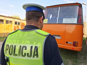 POLICJANT, A W TLE AUTOBUS SZKOLNY