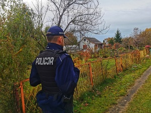 policjant sprawdza teren ogródków działkowych