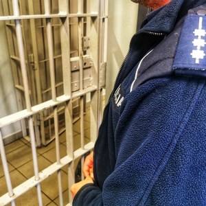 policjant przy kracie aresztu