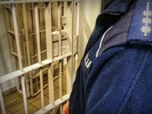 policjant przed kratą aresztu